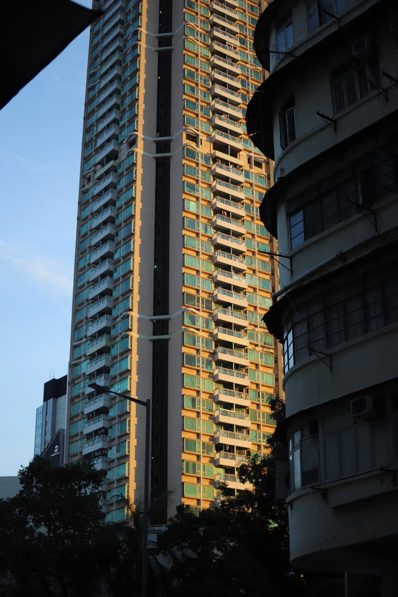 Sunlit high-rise framed by a shadowed curved building
