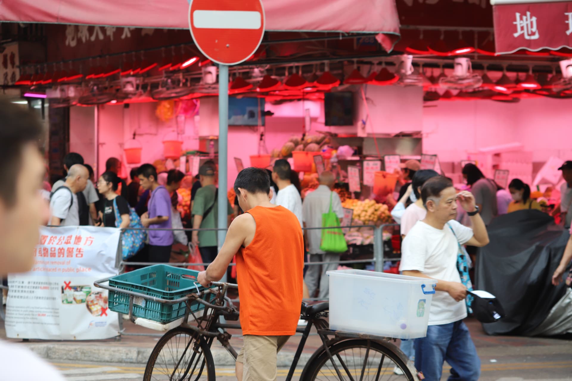 Cyclist crossing a vivid red Hong Kong market