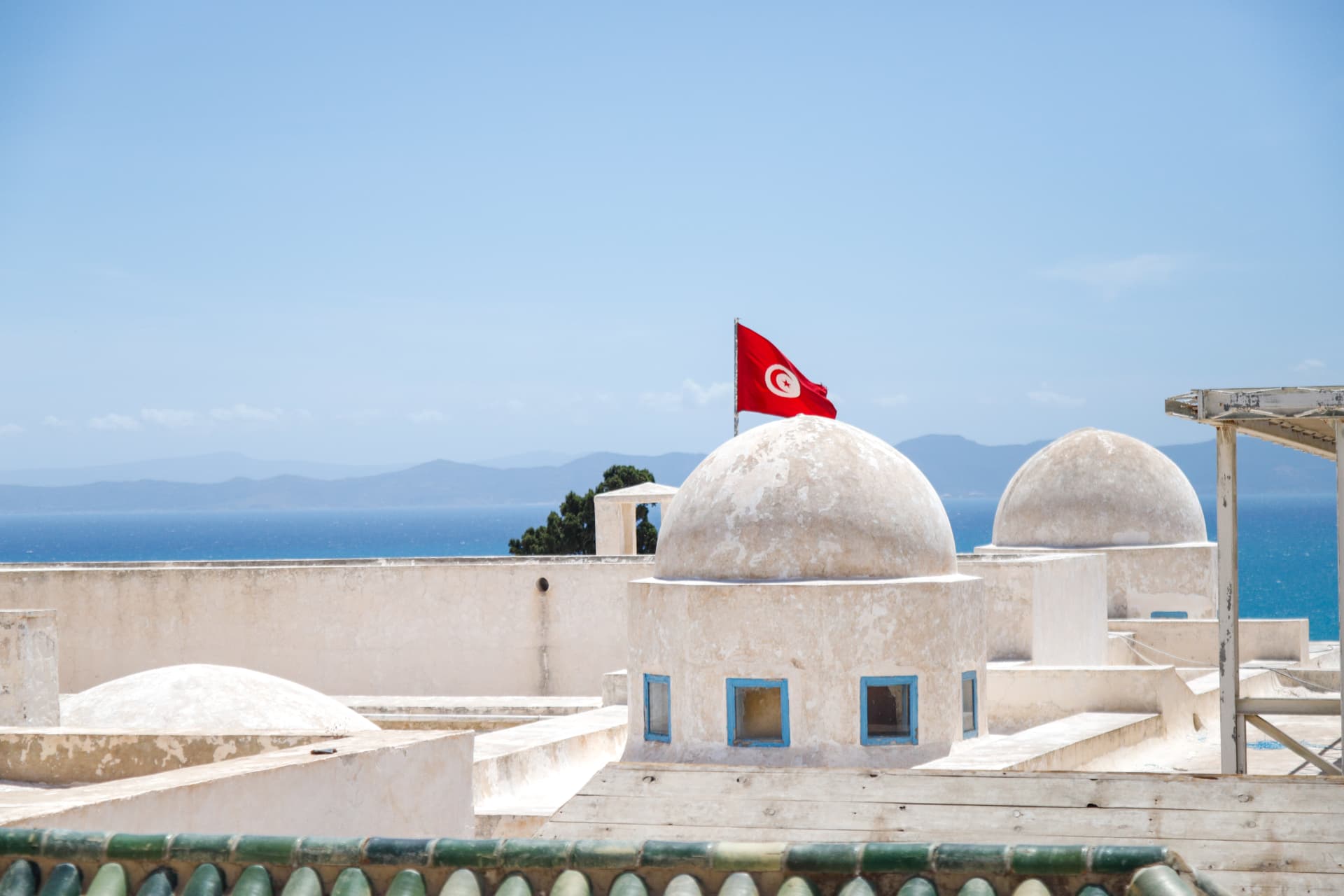White Tunisian domes and flag overlooking blue sea