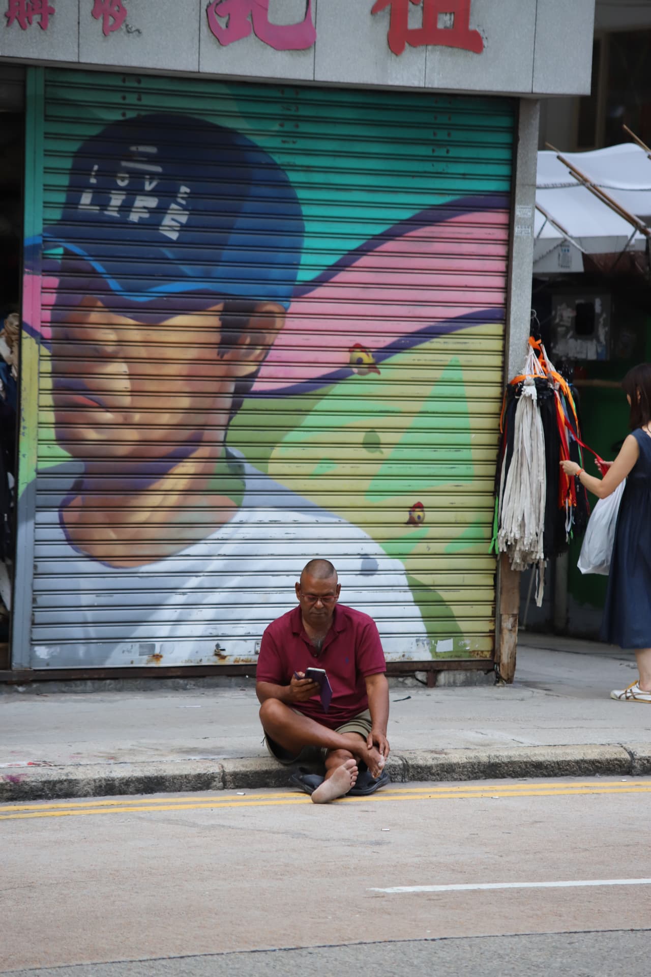 Man sitting before a colorful painted shop shutter